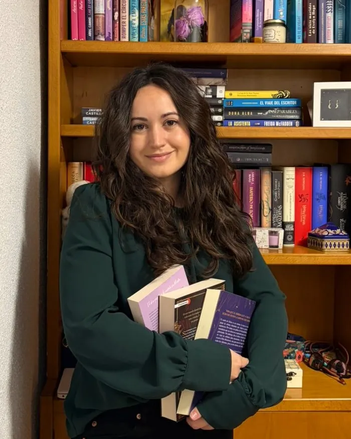 Tania Jiménez con varios libros en las manos, delante de su estantería